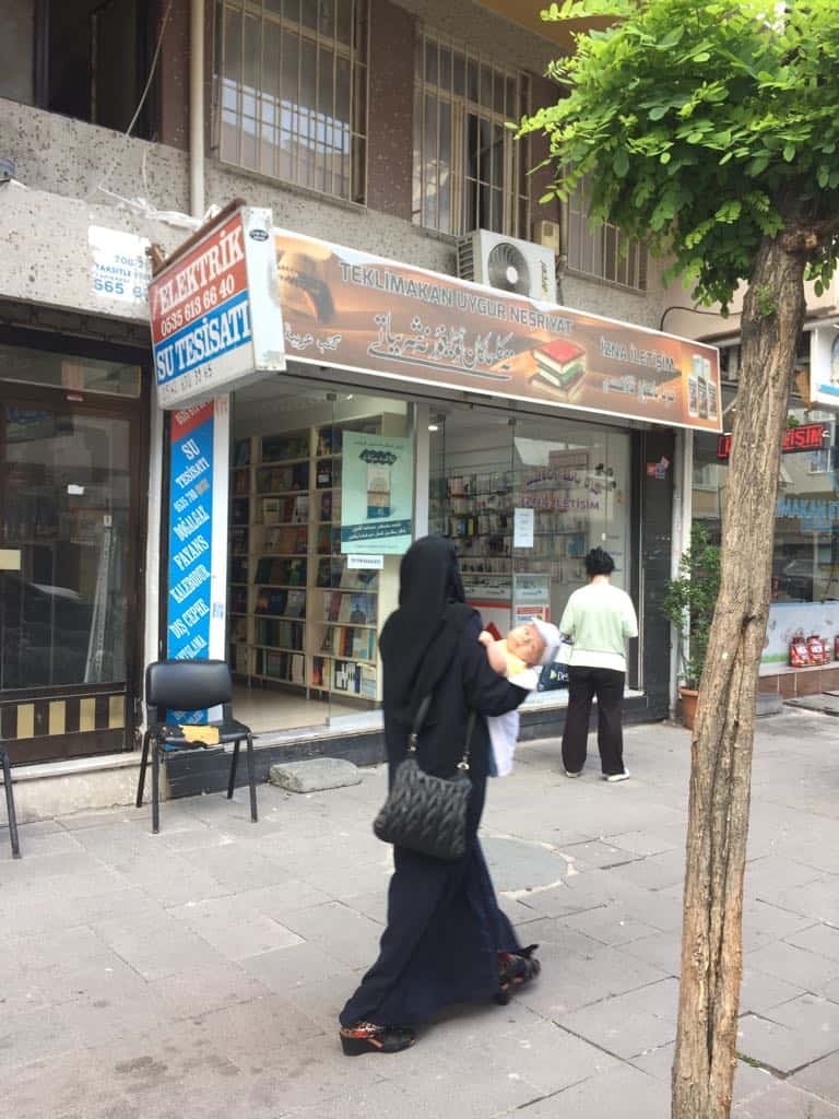 Una “viuda” uigur pasando por una librería uigur en Estambul.