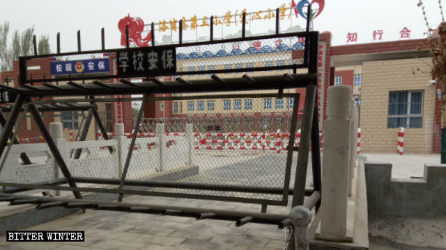 Una escuela primaria en el condado de Lop en Sinkiang acepta a los niños cuyos padres han sido encerrados en campamentos de transformación por medio de educación. La puerta de la escuela está estrictamente vigilada.