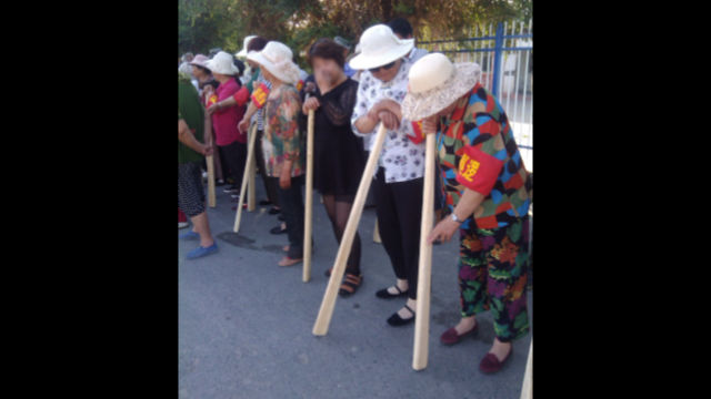 Gente de una localidad de Sinkiang porta bates de madera mientras participan en "simulacros antiterroristas".